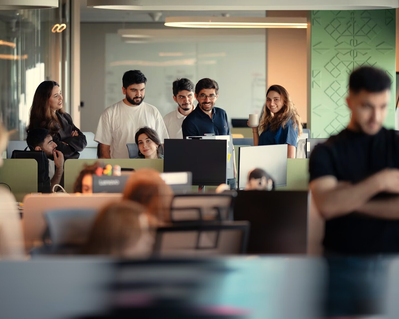 Un equipo mira una pantalla en una oficina mientras alguien pasa caminando adelante